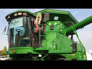 Красивая девушка катается на огромном современном комбайне