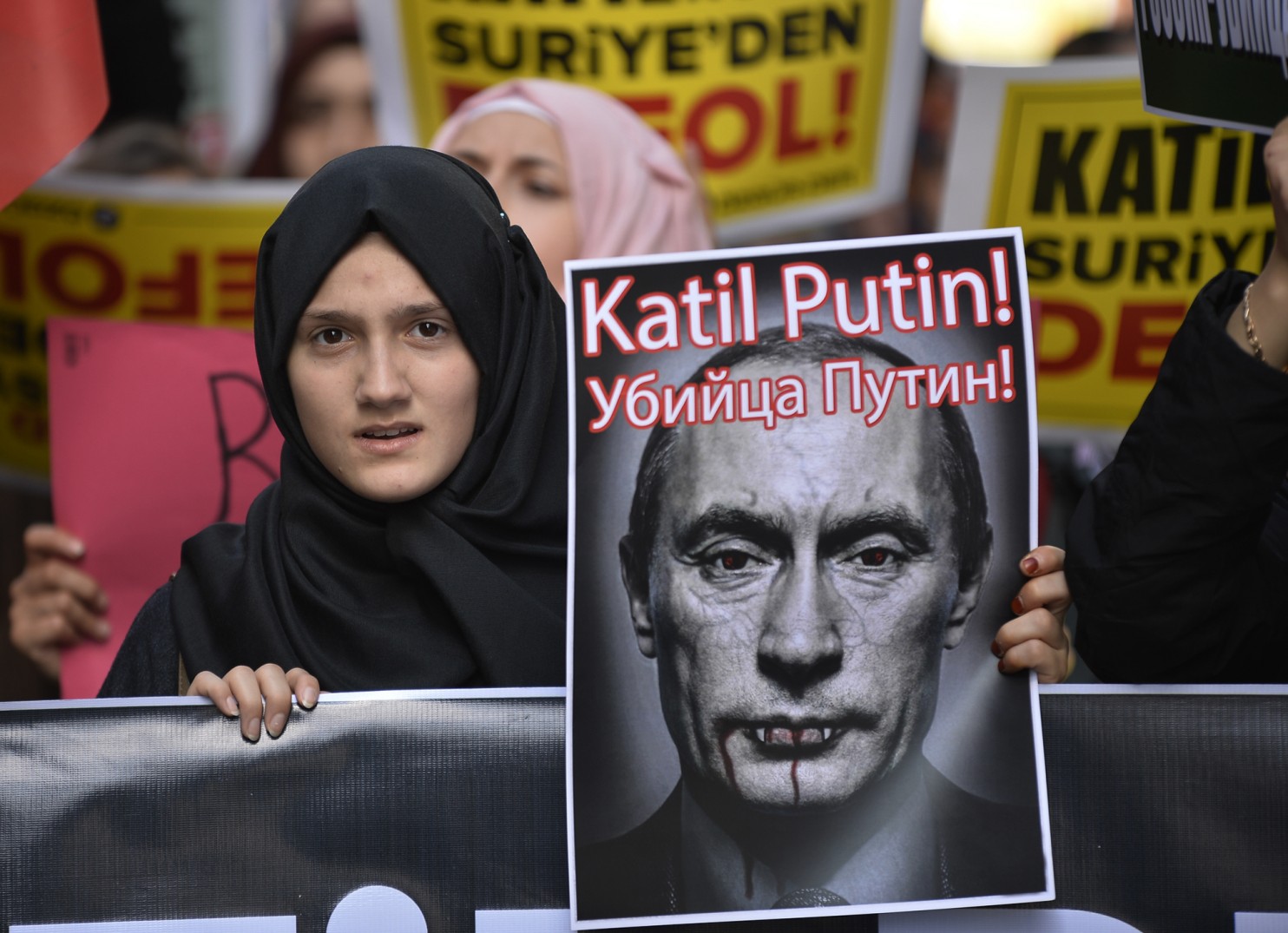 A demonstrator in Istanbul holds a picture depicting Vladimir Putin during a protest against Russian military operations in Syria. It reads in Turkish and Russian: “Murderer Putin.” (Associated Press)